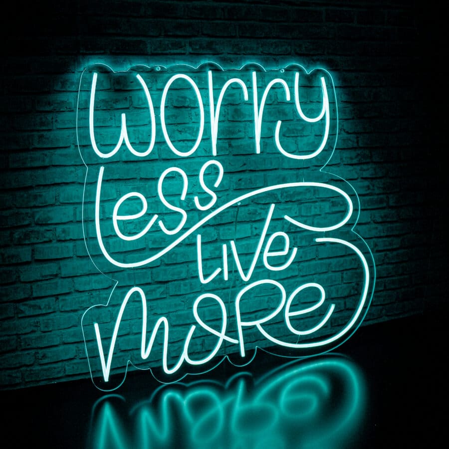 Neón Worry Less Live More en una pared de ladrillos que dice "worry less live more" en letra cursiva estilizada e iluminado con luz azul.