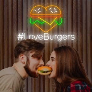 Una pareja compartiendo un tierno beso frente al cartel Neón #LoveBurgers.