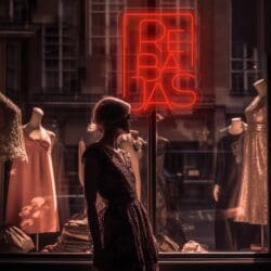 Una mujer está parada frente al escaparate de una tienda Neón Rebajas