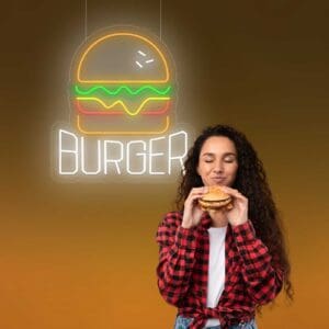 Una mujer disfrutando de una deliciosa burger bajo un fascinante letrero de neón.