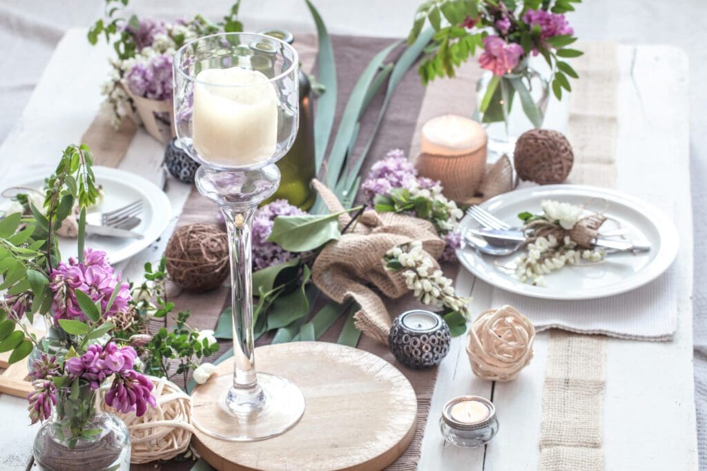 Una mesa con flores de color púrpura y una vela.