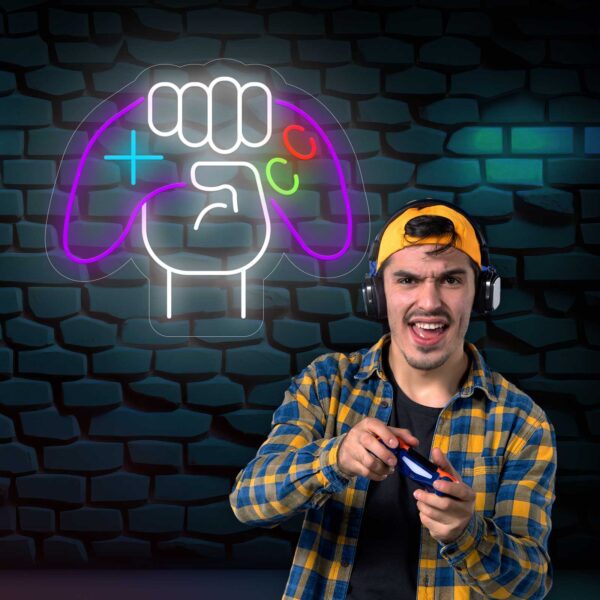 Un joven sujetando un mando de Neón Mando Videojuego frente a un anuncio de Neón Game Zone.