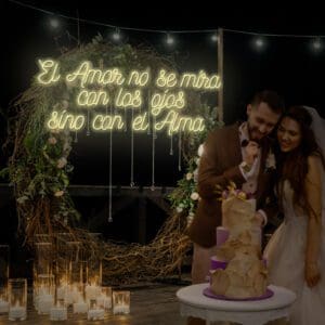 Una novia y un novio cortando un pastel en su boda con el tema Alquiler Neón El Amor No Se Mira Con Los Ojos Sino Con El Alma.