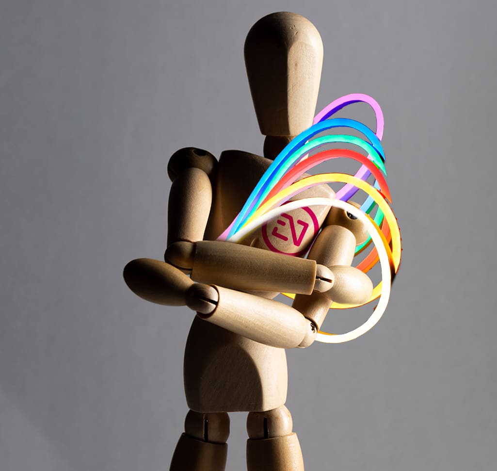 Maniquí de artista de madera sosteniendo un objeto abstracto colorido.