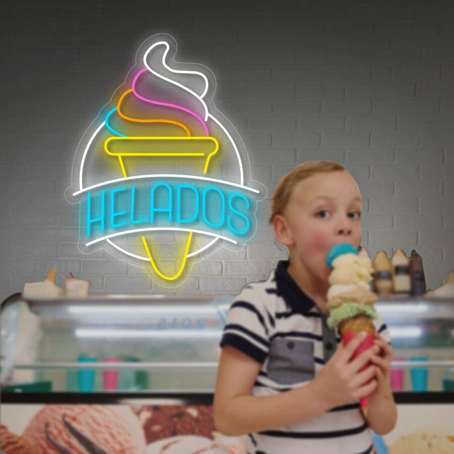 Un niño disfruta de un gran cucurucho de múltiples sabores frente a un cartel de Neón Letrero Helados en una heladería.