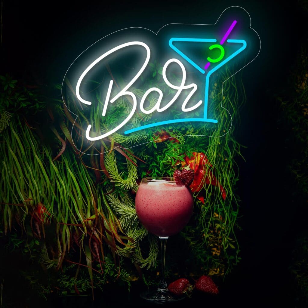 Un letrero de Neón Bar Cócteles que muestra "Bar" con un símbolo de cóctel está iluminado contra una pared cubierta de plantas. Debajo, un batido rosa adornado con fresas se coloca sobre un mostrador, invitándote a tomarte una selfie en este pintoresco entorno.