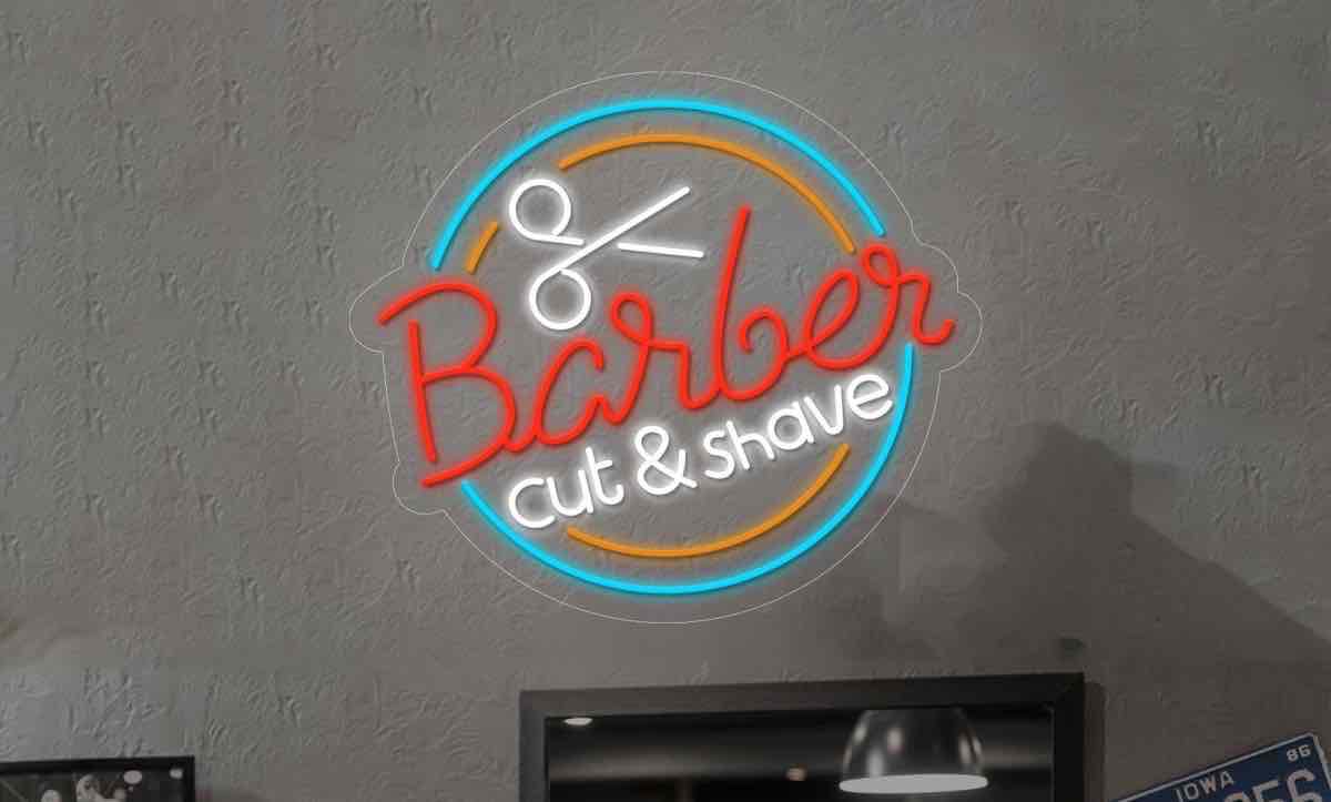 Letrero de neón en una pared que dice "Barber cut & shave" con un icono de tijeras.