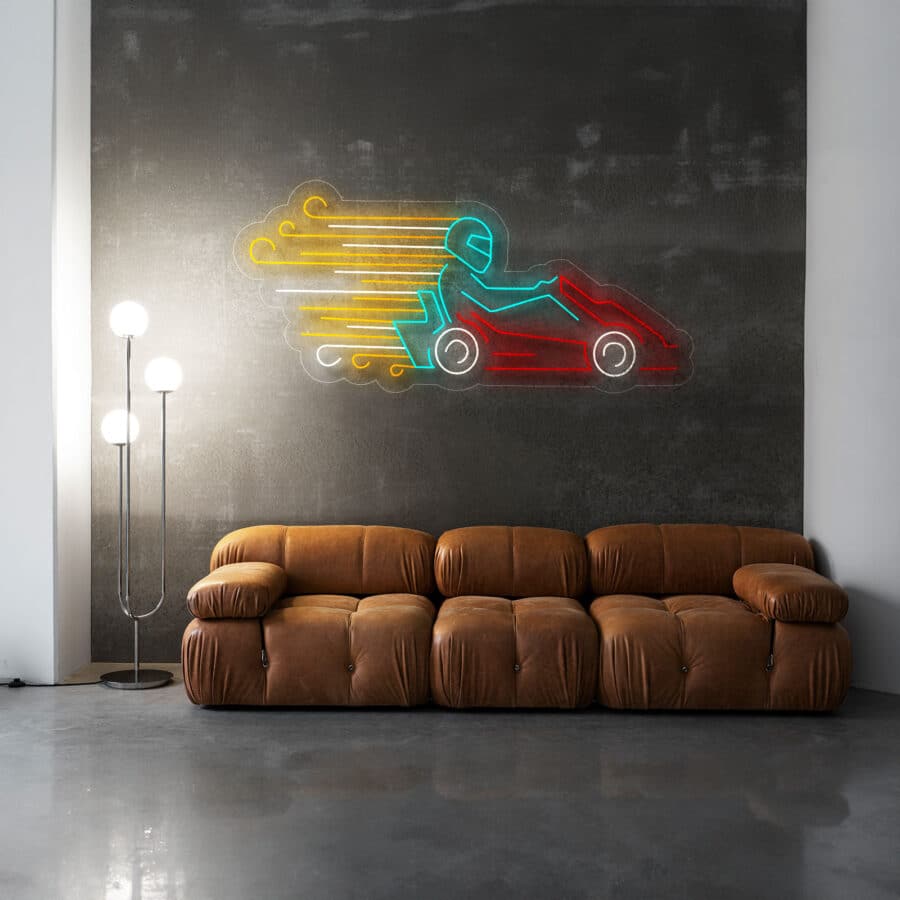 Sofá marrón en una habitación moderna con paredes grises; obra de arte de neón de un kart encima y una lámpara de pie alta con tres globos a la izquierda.