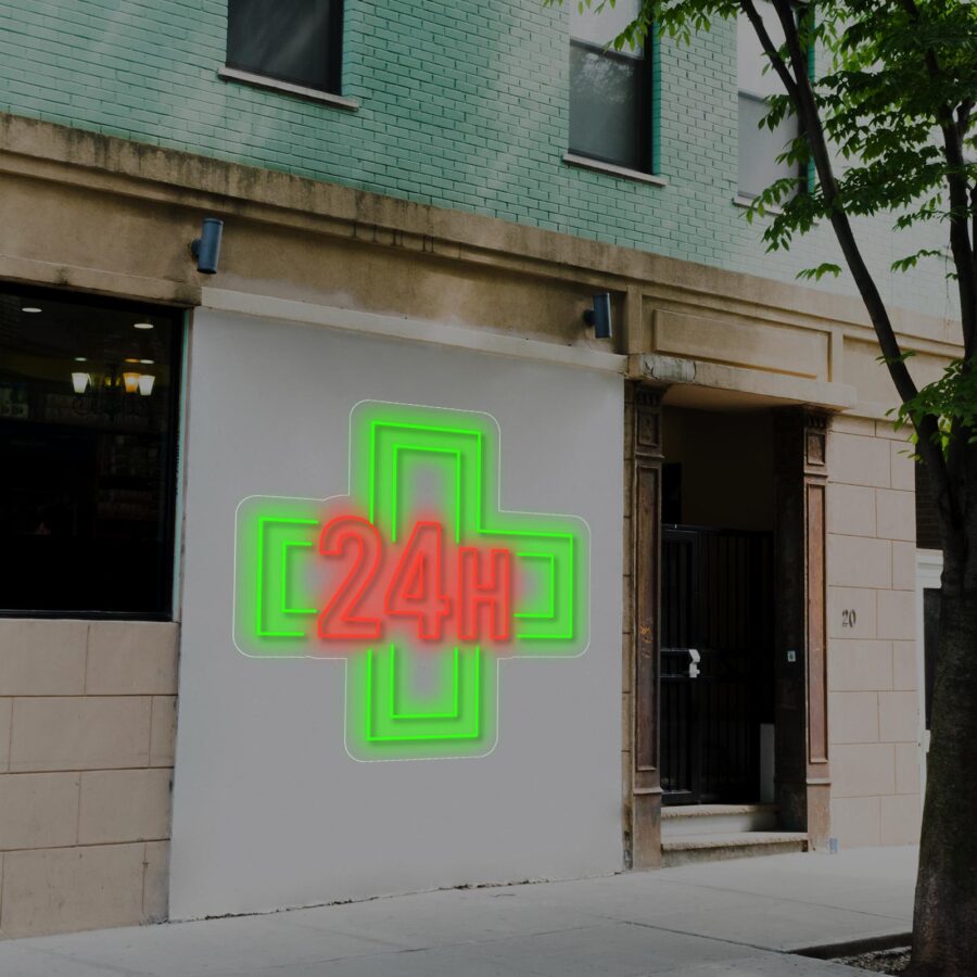 Letrero de neón de una cruz verde con "24H" en rojo, que indica una farmacia abierta las 24 horas, en la pared exterior de un edificio de la ciudad.