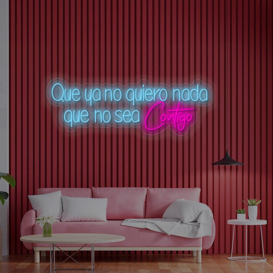 Un letrero de neón en español sobre una pared de paneles rojos encima de un sofá rosa dice: "Que ya no quiero nada que no sea contigo". Mesa de café con plantas al frente.