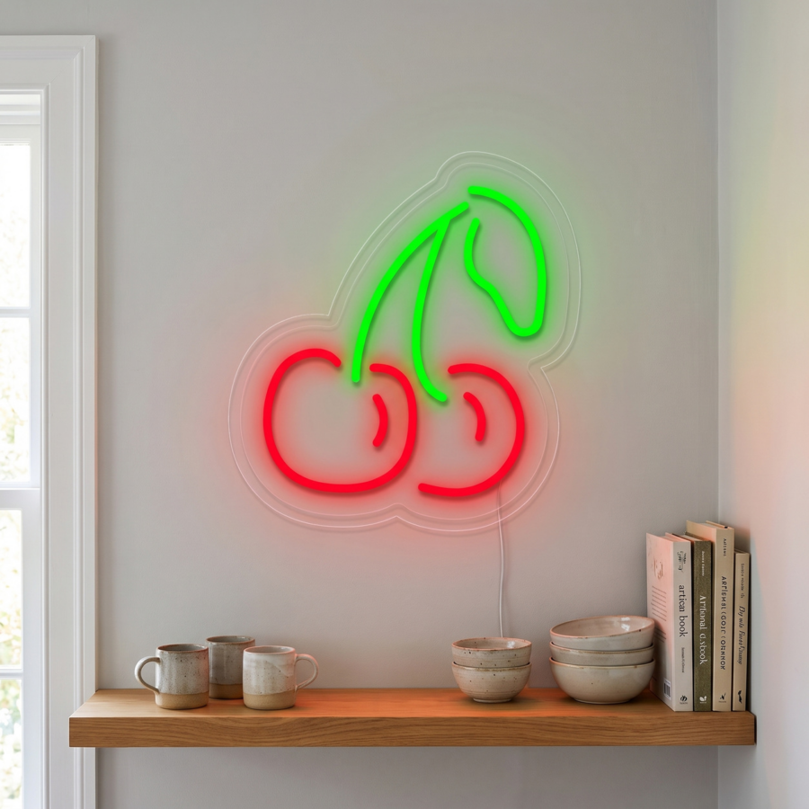 Letrero de neón en la pared con dos cerezas rojas con tallos verdes, colocado sobre una estantería en la que hay apilados cuencos, tazas y varios libros colocados en posición vertical.