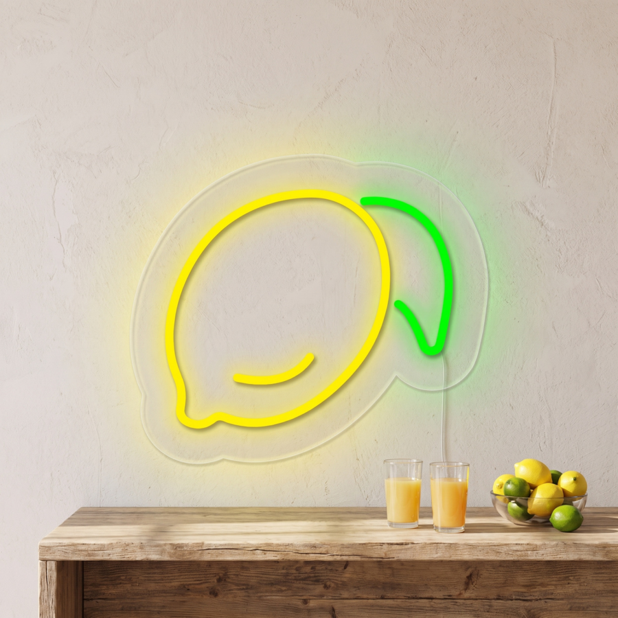Cartel de neón con la palabra «limón» colgado sobre una mesa de madera con dos vasos de zumo de naranja y un cuenco con limones y limas.