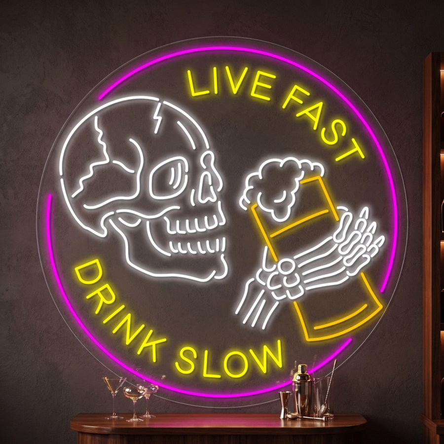 Letrero de neón con la imagen de una calavera que sostiene una jarra de cerveza, con la frase «Live Fast Drink Slow» en luces de neón amarillas y rosas sobre una pared oscura.